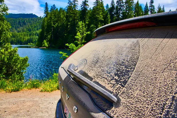 stock image Rugged Volvo covered in dry mud stands by a serene lake in Oregon, surrounded by lush green forest. Perfect for adventurers and nature lovers seeking the ultimate off-road experience in the United