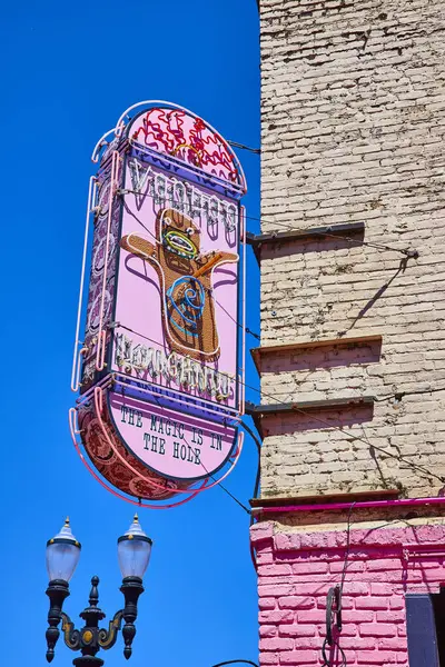 stock image Discover the quirky charm of Voodoo Doughnut in downtown Portland, Oregon. This vibrant neon sign against a clear blue sky captures the unique spirit of a beloved urban bakery known for its creative