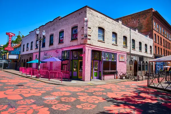 stock image Bright pink Voodoo Doughnut shop in vibrant downtown Portland Oregon under a clear blue sky. Historic brick buildings and colorful street art create a lively urban scene ideal for themes of city life