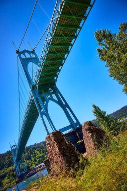 Portland 'daki Katedral Park' taki gök mavisi St Johns Köprüsü 'nün göz kamaştırıcı manzarası. Gotik kuleler ve karmaşık çerçeve verimli bir manzaranın üzerinde yükseliyor, mühendislik dehasıyla doğal güzelliği harmanlıyor.
