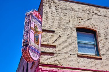 Portland, Oregon şehir merkezinde, parlak mavi gökyüzünün altında, taşralı tuğlalı bir binanın üzerinde canlı neon temalı bir tabela. Eski ve yeninin mükemmel bir karışımı, yerel kültürün ve Amerikanın özünü yakalıyor..