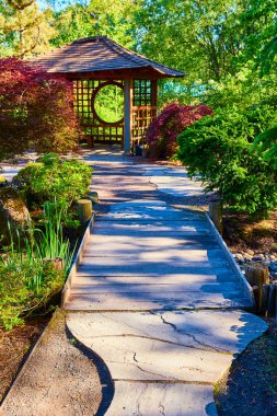 Gresham Japon Bahçesi, Oregon 'daki sakin bahçe sahnesinde, güzel işlenmiş ahşap bir çardak ve dolambaçlı taş bir yolun sonunda dairesel bir açıklık var. Yeşillik sükuneti artırır