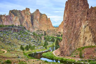 Oregon 'daki Smith Rock State Park' ın engebeli güzelliğini keşfedin. Yüksek kaya oluşumları, yemyeşil yemyeşil ve dingin bir nehir macera ve doğa meraklıları için mükemmel bir manzara yaratır..