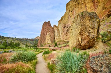 Terrebonne, Oregon 'daki Smith Rock State Park' ın engebeli güzelliğini keşfedin. Bu dingin patika sarp kayalıklardan ve yemyeşil alanlardan geçiyor. Yürüyüşçüler ve macera arayan doğa aşıkları için mükemmel.