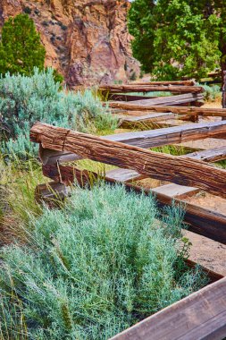 Smith Rock State Parkı 'nın engebeli güzelliği. Yıpranmış ahşap kirişler yemyeşil yemyeşil arka planda yükselen kaya oluşumları arasında yatıyordu. Doğa dayanıklılığı ve tarihi derinlik bu manzarada birleşir.