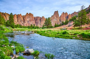 Huzurlu nehir manzarası Smith Rock State Park, Oregon 'da. Yükselen kaya oluşumları ve yemyeşil yeşillik açık hava macerası, korunma ve manzaranın takdir edilmesi için mükemmel bir ortam yaratır..