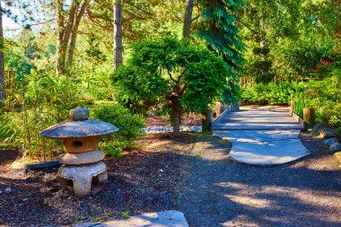 Oregon 'daki Serene Gresham Japon Bahçesi yolu, canlı yeşillikler, yıpranmış taş bir fener ve pürüzsüz taş kaldırım. Seyahat, peyzaj ve refah geri çekilme temaları için mükemmel..