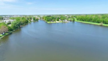 Varşova Indiana 'daki pitoresk göl evlerinin hava üssü. Berrak bir mavi gökyüzü altında yemyeşil ve antika evlerle çevrili sakin göl sakin bir banliyö yaşam tarzını yakalar..