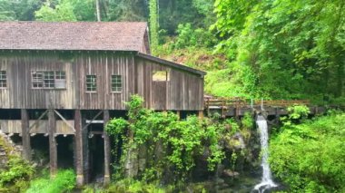 Woodland Washington 'daki Cedar Creek Grist Mill' in hava izleme görüntüsü. Yıpranmış ahşap değirmeni yemyeşil bir alana kurulmuş görünür bir su tekeriyle köy cazibesini, tarihsel önemi ve...