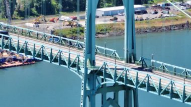 Portland, Oregon 'daki St. Johns Köprüsü' nün çarpıcı görüntüsü. Zarif turkuaz mimari, hareket halindeki araçlar ve sakin Willamette Nehri kentsel güzelliği vurguluyor.
