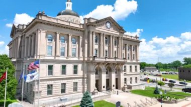 Birleşik Devletler 'in ileri uçuşu Indiana Huntington Adliyesi büyük mimari saat kulesini ve açık mavi gökyüzünü canlı yeşillik ve bayraklarıyla gösteren kubbesini sergiliyor.