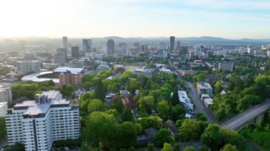 Altın saat boyunca Portland Oregon şehir merkezinin gökyüzü manzarasında yüksek binalar yemyeşil alanlar ve önemli bir spor stadyumu sergilenmektedir. Kentsel ve doğa karışımı Portlands 'ı canlı ve canlı vurguluyor.