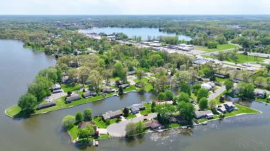 Aerial Fly Over Forward: Serene airial air view of Varşova, Indiana, picoresque lake house, yemyeşil ve parlak sular sergilenmektedir. Huzur ve gölde yaşamak için mükemmel bir örnek.