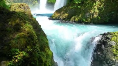 Washington 'daki Columbia Vadisi' ndeki Spirit Falls 'u kayalık arazide şelale gibi akan turkuaz sularla yakalayan yayalar. Bereketli yeşilliklerle çevrelenmiş canlı sahne, el değmemiş doğaları sergiliyor.