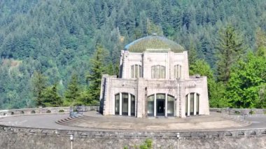 Oregon 'daki Crown Point' teki tarihi Vista House 'un göz kamaştırıcı görüntüsü. Sekizgen taş yapı, kemerli pencereler ve fayanslı kubbe çatısı yemyeşil ortamda duruyor.