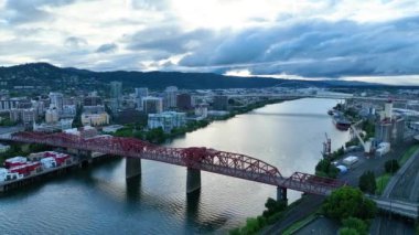 Hava İzleme Çekimi: Willamette Nehri 'ni kaplayan ikonik kırmızı Broadway Köprüsü' nün yer aldığı Portland, Oregon 'un çarpıcı görüntüsü. Bereketli yeşile karşı kurulmuş canlı şehir manzarasını yakalayın