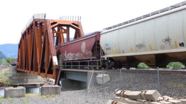 Stevenson, Washington 'daki Rüzgâr Nehri Köprüsü, gür Columbia Boğazı' na karşı pas rengi ve heybetli duruyor. Bir BNSF treni kesişiyor, dinamik endüstriyel etkinlik ekliyor