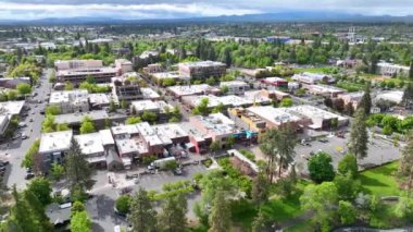 Oregon şehir merkezinin hava yayı çekimi modern ve tarihi binalarla dolu canlı şehir manzarasını sergiliyor. Yeşillik ve ağaçlarla kaplı sokaklar manzaralı dağların arka planına karşı kurulmuş.