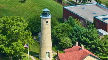 Wisconsin 'deki Kenosha Southport Işık İstasyonu' nun havadan görünüşü, yemyeşil, kırmızı çatılı bir bina ve bir Amerikan bayrağı arasında klasik bir deniz feneri sergiliyor. Seyahat, tarih ve...