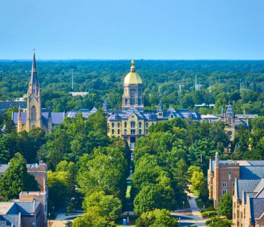 South Bend, Indiana 'daki Notre Dame Üniversitesi kampüsünün hava manzarasında ikonik Altın Kubbe ve Kutsal Kalp Bazilikası yer alıyor. Yeşillik ve tarihi mimari huzur yaratır.