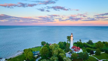 Günbatımında, beyaz dış ve kırmızı çatısı Michigan Gölü 'nün yanında duran Wisconsin Rüzgâr Noktası Deniz Feneri' nin hava manzarası. Etrafı yemyeşil ve dingin sularla çevrili.