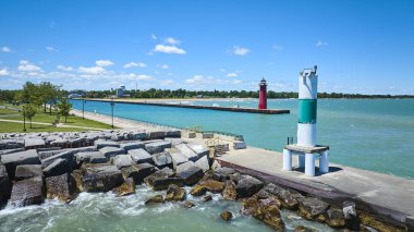 Michigan Gölü 'ne uzanan bir iskelede, Kenosha, Wisconsin' de sakin bir parkı ve dalgalı bir dalgakıranı olan canlı kırmızı deniz fenerinin havadan görüntüsü. Seyahat ve kıyı yaşamı için mükemmel bir yaz manzarası.