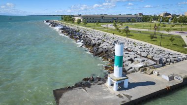 Kenosha, Wisconsin 'deki bir rıhtımdaki beyaz ve yeşil deniz fenerinin havadan görünüşü. Huzurlu sahnede Michigans Gölü 'nün turkuaz dalgaları, bir kıyı parkı ve modern binalar yer alıyor.