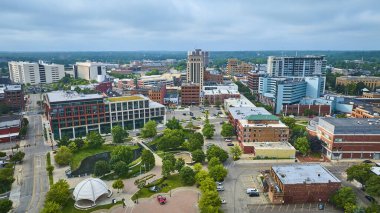 Kalamazoo, Michigan şehir merkezinin canlı hava manzarası, modern ve tarihi binaların karışımı, bereketli şehir parkı ve parçalı bulutlu bir gökyüzü altında dönen Arcadia Deresi. Şehir için mükemmel.