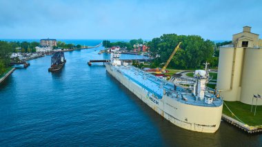 St. Joseph Nehri 'ndeki Benton Limanı' nın havadan görünüşü sanayi siloları yakınında bir Holcim kargo gemisi, botlarla dolu bir yat limanı ve göl kıyısında manzaralı bir deniz kenarı topluluğu.