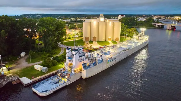 stock image Aerial view of a bustling industrial barge named HOLCIM docked at a facility along the St. Joseph River in Benton Harbor, Michigan, during early evening, highlighting logistics and manufacturing