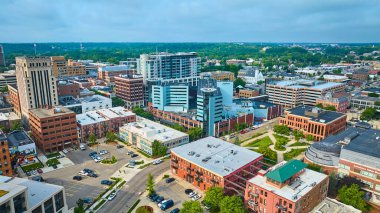 Kalamazoo, Michigan şehir merkezinin hava görüntüsü modern ve tarihi mimarinin canlı bir karışımını sergiliyor. Yeşil alanlar ve yemyeşil bir banliyö arka planı şehirleri dengeli kentsel ve doğal olarak ön plana çıkarıyor