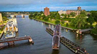 Alacakaranlıkta Benton Harbor, Michigan 'ın havadan görünüşü: St. Joseph Nehri' ne büyük bir kargo gemisi yanaştı, kısmen yükseltilmiş bir asma köprü, ve kentsel yaşam ve sakin parkların bir karışımı. Gerçekten mükemmel.