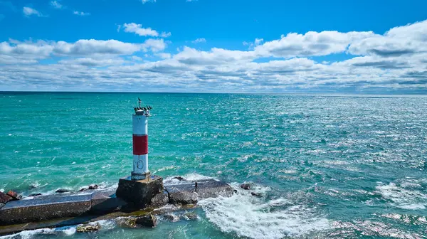 stock image Serene aerial view of Kenosha lighthouse on a rocky breakwater extending into Lake Michigans blue waters, capturing themes of navigation, safety, and tranquility under a clear, sunny sky. Perfect for