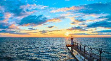 Michigan Gölü 'nde altın saat. St. Joseph North Pier Deniz Feneri günbatımında gemilere rehberlik ediyor. Sakin sular, dingin gökyüzünü yansıtır. Huzurlu ve resimli bir deniz manzarası yaratır..