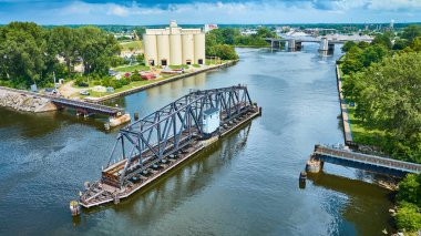 Benton Limanı St. Joseph Nehri 'nin havadan görünüşü, açık bir siyah metal salıncak köprüsü, endüstriyel yapılar ve verimli yeşillikler, doğa ve endüstrinin ahenkli karışımını gözler önüne seriyor.