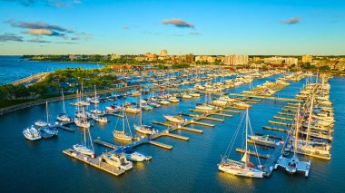 Güneşin doğuşunda Wisconsin, Racine 'de canlı bir yat limanının havadan görüntüsü. Michigan Gölü 'ne yanaşan yelkenliler ve yatlar, şehir manzarası ve yeşilliklerle birlikte manzaralı bir manzara yaratıyor.