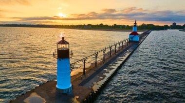 Serene aerial view of Lake Michigan at sunset with two iconic lighthouses on North Pier in St. Joseph. The white and black Inner Lighthouse and the red-roofed Outer Lighthouse stand as timeless clipart