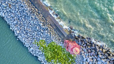 Wisconsin 'deki Racine Breakwater Deniz Feneri' nin hava manzarası Michigan Gölü 'nün engebeli kayaları ve turkuaz dalgalarıyla çevrili. Kırmızı yapı, doğal deniz manzarasıyla çelişiyor. Huzur uyandırıyor.