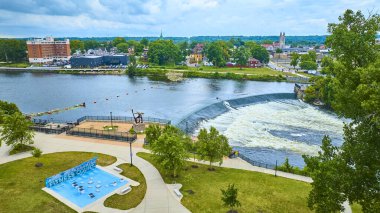 Indiana 'daki Mishawaka Central Park' ın havadan görünüşü, küçük bir şelale, yeşil çimenler ve modern sanatla serin St. Joseph nehrine ev sahipliği yapar. Doğa ve şehir yaşamının bir fitness ile resimsel bir karışımı