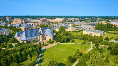 Aerial view of Notre Dame University in South Bend, Indiana, showcasing Gothic-style buildings, lush green spaces, and the iconic stadium, under a clear blue sky, highlighting tradition and community. clipart