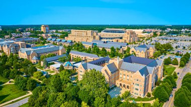 South Bend, Indiana 'daki Notre Dame Üniversitesi' nin hava manzarası akademik binalar, yemyeşil yollar ve büyük bir stadyum gösteriyor. İkonik kule duvar resmi bu canlılığa kültürel değer katıyor.
