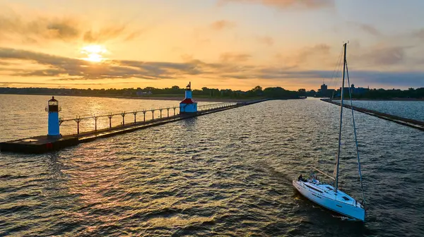 stock image Golden hour over Lake Michigan captures St. Josephs iconic North Pier Lighthouse and a sailboat gliding through calm waters. The tranquil scene embodies relaxation and the simple pleasures of coastal