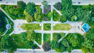 Aerial view of Bronson Park in downtown Kalamazoo, Michigan, showcasing symmetrical pathways, vibrant floral arrangements, lush green quadrants, and a soothing water feature, offering a peaceful urban clipart