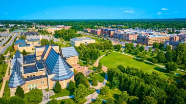 Aerial view of South Bends vibrant urban area featuring the architecturally unique Performing Arts Center at Notre Dame University, surrounded by lush greenery and a serene public park. clipart