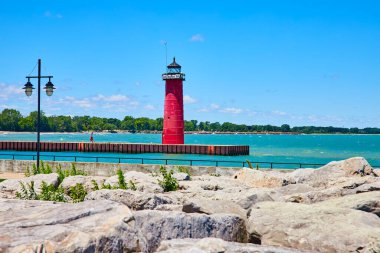 Kenosha rıhtımındaki canlı kırmızı deniz feneri Michigan Gölü 'ne kadar uzanır, sakin mavi bir gökyüzü ve yeşil ağaçlar tarafından çerçevelenir. Wisconsin, ABD 'de seyahat, sükunet ve deniz rehberliği konuları için mükemmel..