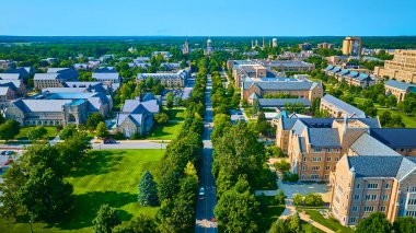 Aerial view of Notre Dame campus in South Bend, Indiana, showcasing symmetrical grey slate-roofed academic buildings, lush green lawns, and a central tree-lined avenue leading to a golden-domed clipart