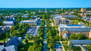 South Bend, Indiana 'daki Notre Dame Üniversitesi kampüsünün hava manzarasında ağaç kaplı cadde, gotik mimari ve yemyeşil çimenler yer alıyor. Akademik mükemmellik ve huzur içinde öğrenme için ideal.