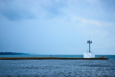 Benton Harbor, Michigan 'daki South Pier Deniz Feneri' nin sakin deniz manzarası. Beton iskele, bulutlu bir gökyüzü altında Michigan Gölü 'nün sakin sularına doğru uzanıyor. Yalnızlık ve deniz yolculuğunu çağrıştırıyor. Tam oldu.