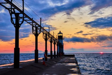 Benton Limanı deniz feneri, Michigan 'da gün batımı. Kuzey İskelesi, Michigan Gölü 'nün sakin sularını yansıtan renkli bir gökyüzüne karşı durmaktadır. Rehberlik, sükunet ve sahil temaları için mükemmel.