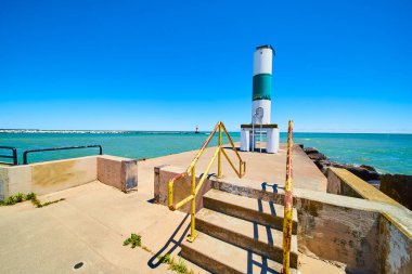 Michigans Gölü Kenosha Rıhtımı 'nda sakin bir gün. Bir beyaz ve yeşil gün feneri, denizcilik faaliyetlerine rehberlik eden uzun bir yol göstericidir. Sakin sular ve uzak bir deniz feneri huzurlu manzarayı oluşturur. Tam oldu.